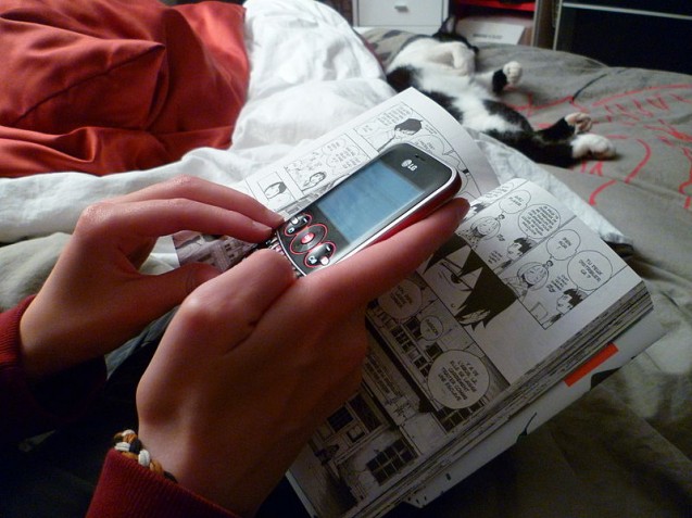 800px-Teenage_girl_texting_while_reading_a_manga_1