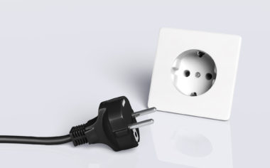 european disconnected black plug lies on the ground in front of a white socket